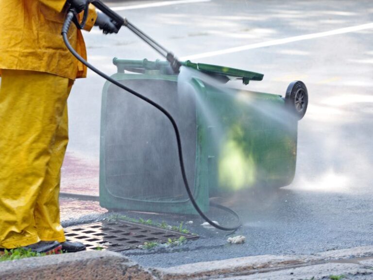 Man in yellow outfit cleaning a trash bin